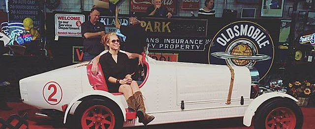 An auctioneer sitting in a classic car